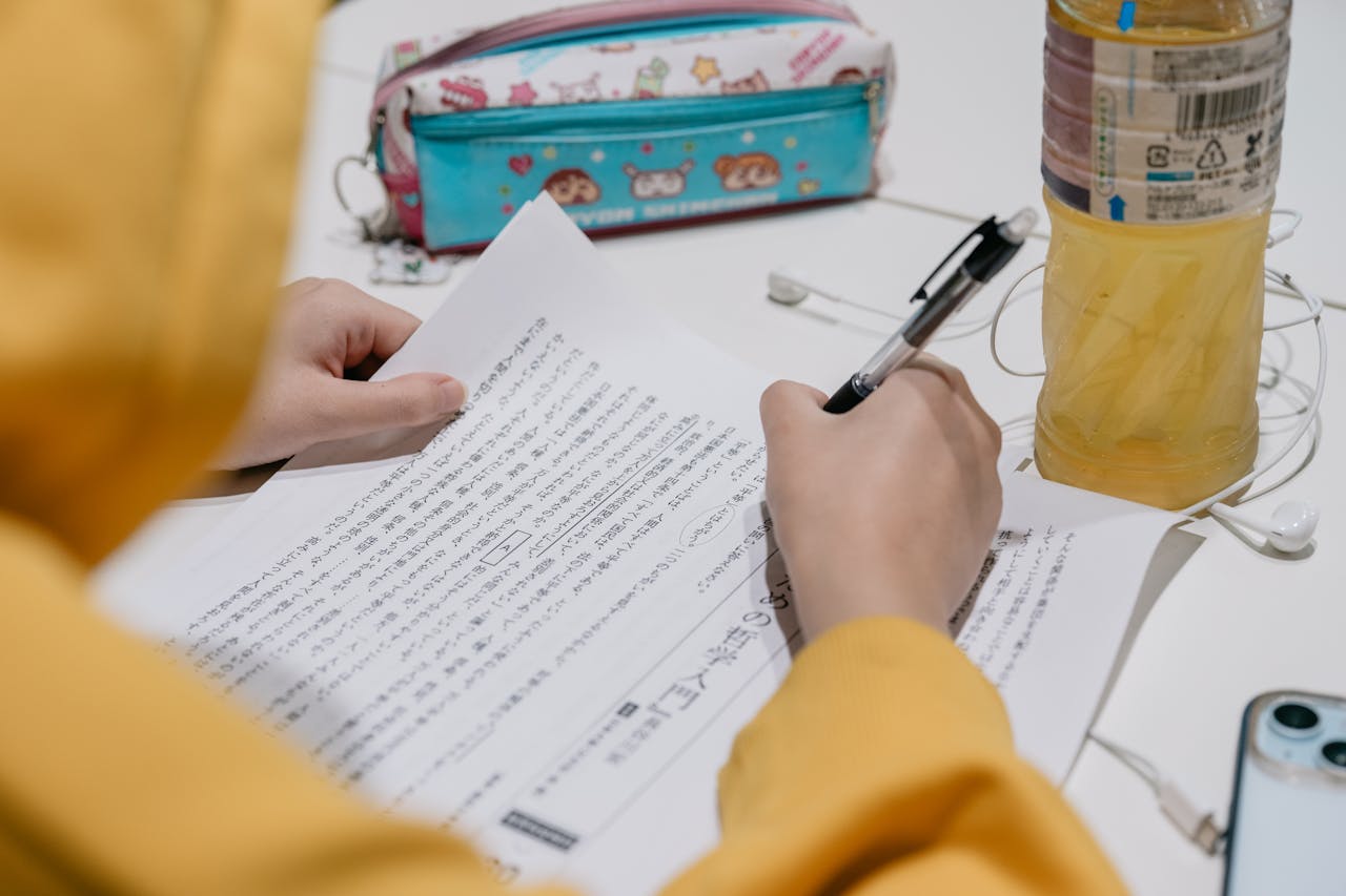 services-03 Close-up of individual studying Japanese text with colorful stationery on desk.